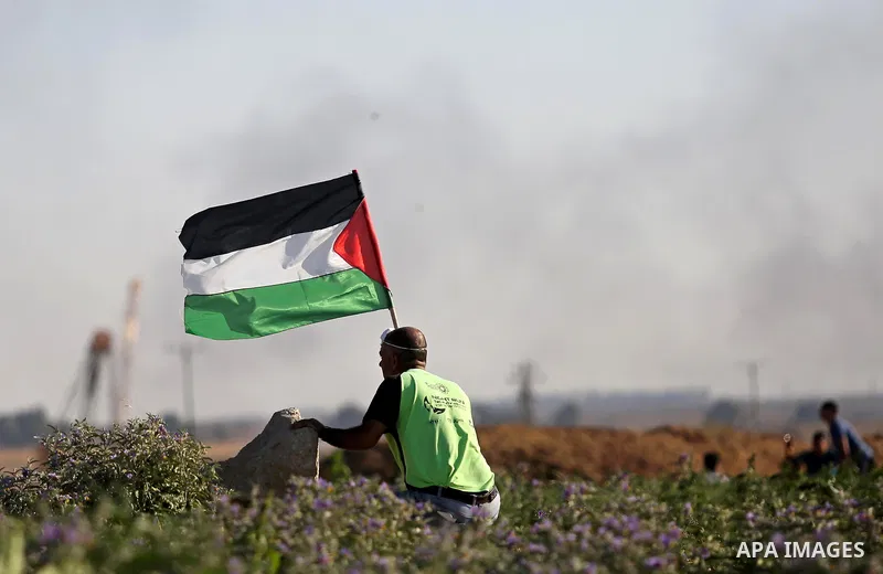A Palestinian protester waves the national during clashes with Israeli security forces following a protest near the border fence east of Jabalia refugee camp, against the blockade on the Gaza Strip on June 5, 2017. Photo...