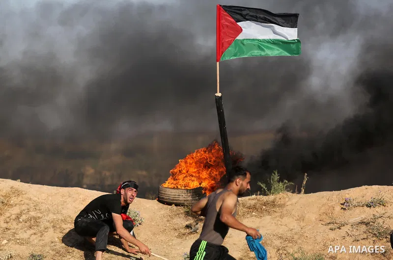 A Palestinian protester takes cover during clashes with Israeli security forces following a demonstration against the blockade on the Gaza Strip, near the border fence east of Jabalia refugee camp on June 5, 2017. Photo...