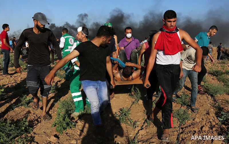 Palestinian protesters carry a wounded man during clashes with Israeli security forces following a demonstration against the blockade on the Gaza Strip, near the border fence east of Jabalia refugee camp on June 5, 2017....
