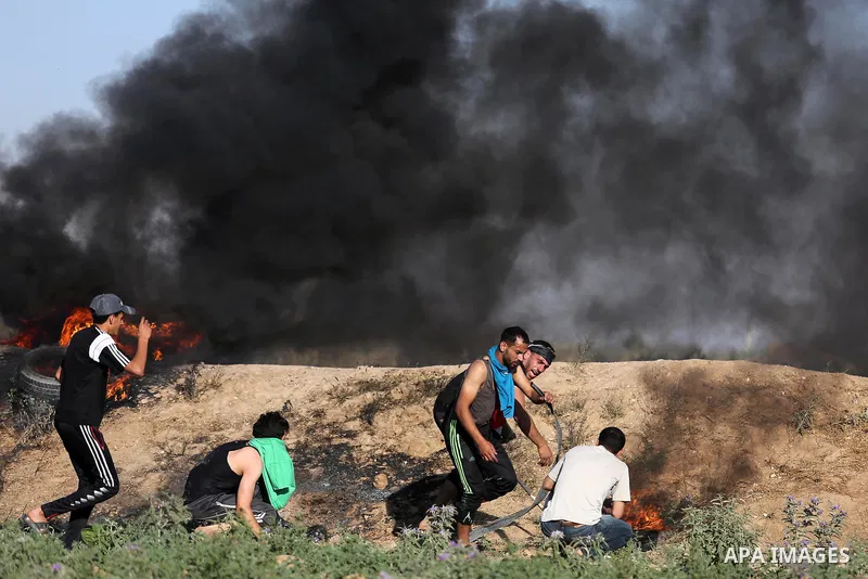 Palestinian protesters take cover during clashes with Israeli security forces following a demonstration against the blockade on the Gaza Strip, near the border fence east of Jabalia refugee camp on June 5, 2017. Photo by...