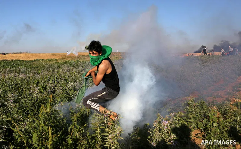 A Palestinian protester takes cover during clashes with Israeli security forces following a demonstration against the blockade on the Gaza Strip, near the border fence east of Jabalia refugee camp on June 5, 2017. Photo...