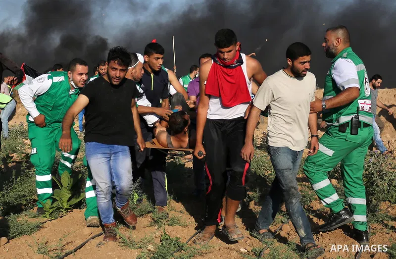 Palestinian protesters carry a wounded man during clashes with Israeli security forces following a demonstration against the blockade on the Gaza Strip, near the border fence east of Jabalia refugee camp on June 5, 2017....
