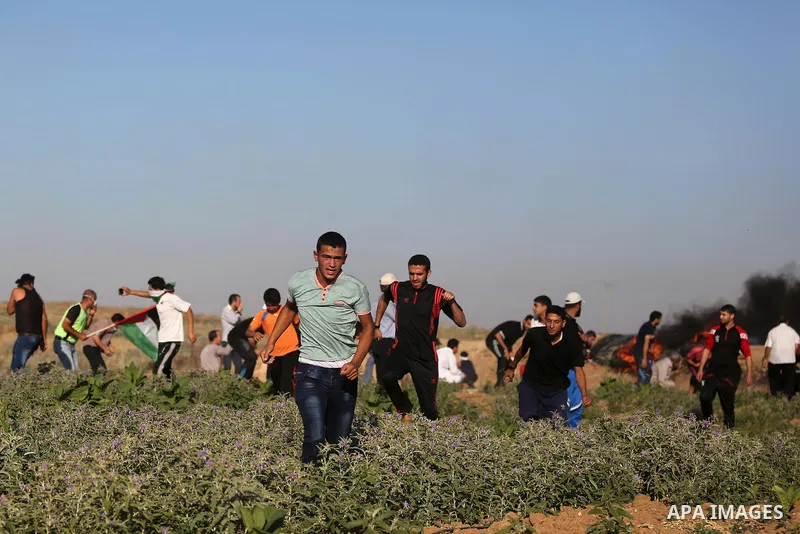 Palestinian protesters take cover during clashes with Israeli security forces following a demonstration against the blockade on the Gaza Strip, near the border fence east of Jabalia refugee camp on June 5, 2017. Photo by...