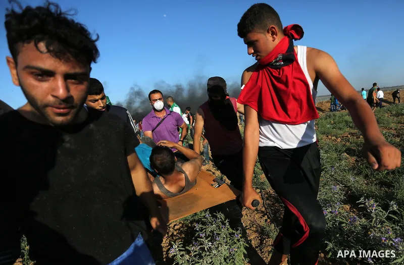 Palestinian protesters carry a wounded man during clashes with Israeli security forces following a demonstration against the blockade on the Gaza Strip, near the border fence east of Jabalia refugee camp on June 5, 2017....