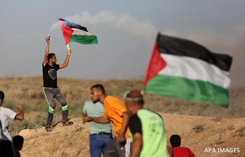 A Palestinian protester hold the national flag and a tear gas canister fired by Israeli security froces during clashes following a demonstration against the blockade on the Gaza Strip, near the border fence east of Jabal...