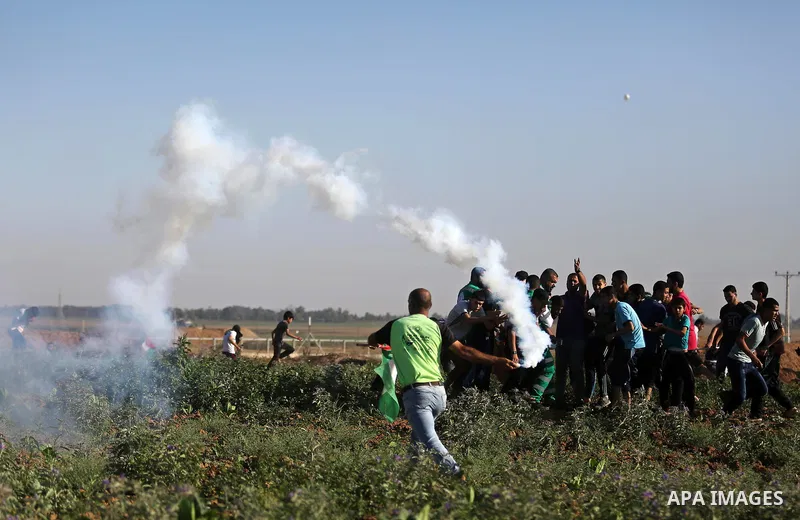 A Palestinian protester throws a tear gas canister towards Israeli security forces during clashes following a demonstration against the blockade on the Gaza Strip, near the border fence east of Jabalia refugee camp on Ju...