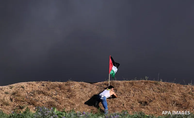 A Palestinian protester waves the national during clashes with Israeli security forces following a protest near the border fence east of Jabalia refugee camp, against the blockade on the Gaza Strip on June 5, 2017. Photo...