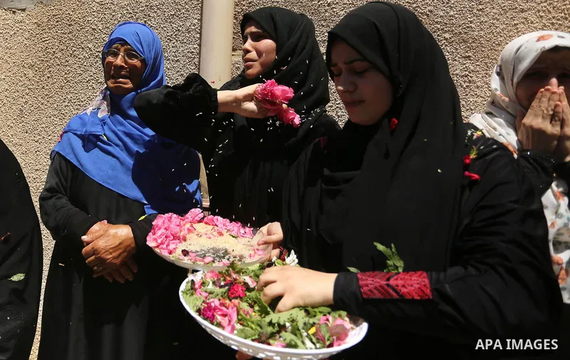 Mourners throw flowers at the body of a 25-year-old Palestinian Fadi al-Najjar who was killed by Israeli fire in the Gaza Strip during clashes with Israeli sceurity forces at the border fence the previous day, during his...