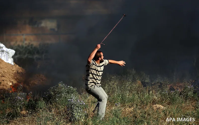 A Palestinian protester uses a slingshot to hurl stones towards Israeli security forces during clashes following a demonstration against the blockade on the Gaza Strip, near the border fence east of Jabalia refugee camp...