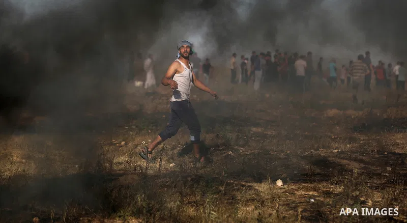 A Palestinian protester takes cover during clashes with Israeli security forces following a demonstration against the blockade on the Gaza Strip, near the border fence east of Jabalia refugee camp on June 7, 2017. Photo...
