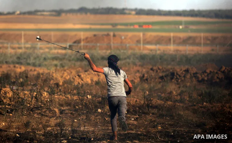 A Palestinian protester uses a slingshot to hurl stones towards Israeli security forces during clashes following a demonstration against the blockade on the Gaza Strip, near the border fence east of Jabalia refugee camp...