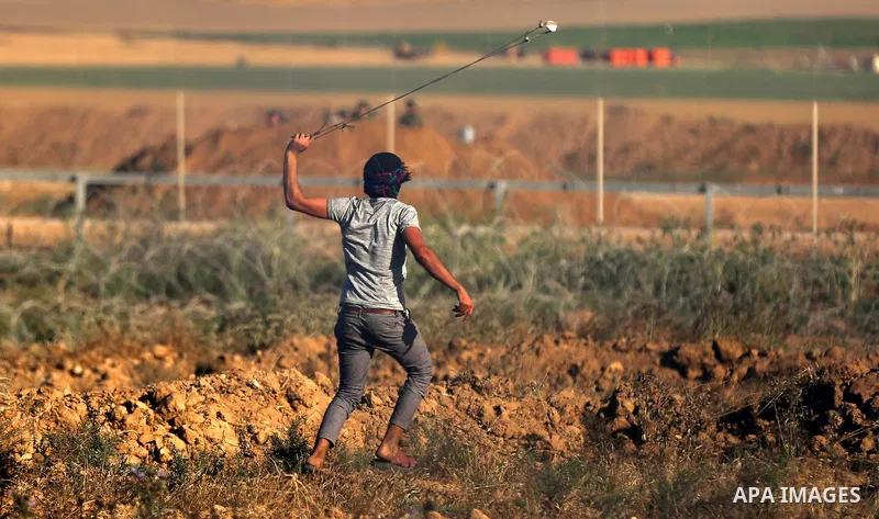 A Palestinian protester uses a slingshot to hurl stones towards Israeli security forces during clashes following a demonstration against the blockade on the Gaza Strip, near the border fence east of Jabalia refugee camp...