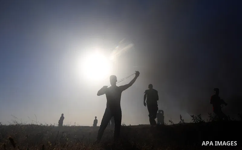A Palestinian protester uses a slingshot to hurl stones towards Israeli security forces during clashes following a demonstration against the blockade on the Gaza Strip, near the border fence east of Jabalia refugee camp...
