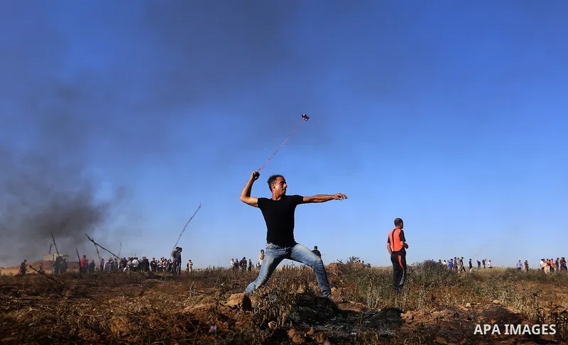 A Palestinian protester uses a slingshot to hurl stones towards Israeli security forces during clashes following a demonstration against the blockade on the Gaza Strip, near the border fence east of Jabalia refugee camp...