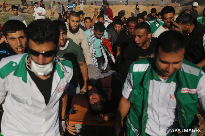 Palestinian protesters carry a wounded man during clashes with Israeli security forces following a demonstration against the blockade on the Gaza Strip, near the border fence east of Jabalia refugee camp on June 7, 2017....