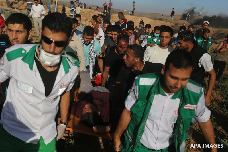Palestinian protesters carry a wounded man during clashes with Israeli security forces following a demonstration against the blockade on the Gaza Strip, near the border fence east of Jabalia refugee camp on June 7, 2017....