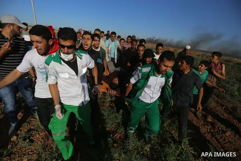 Palestinian protesters carry a wounded man during clashes with Israeli security forces following a demonstration against the blockade on the Gaza Strip, near the border fence east of Jabalia refugee camp on June 7, 2017....