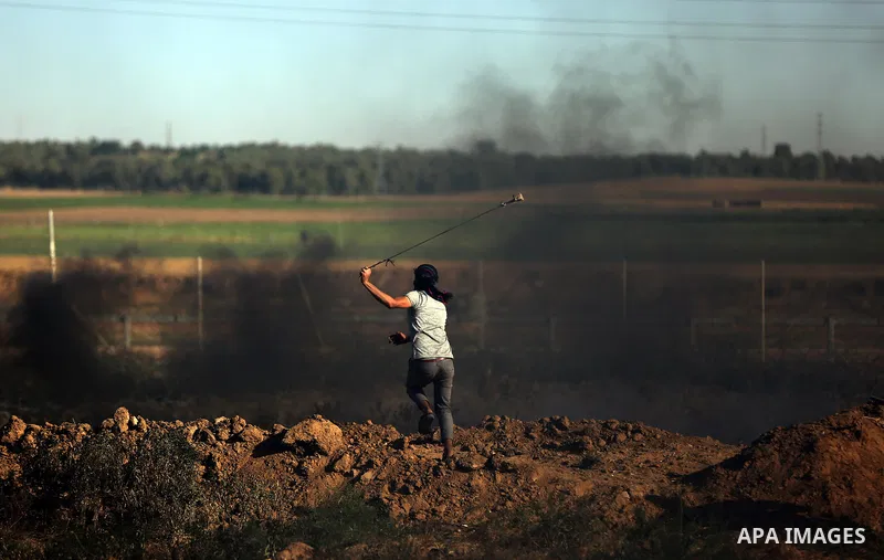 A Palestinian protester uses a slingshot to hurl stones towards Israeli security forces during clashes following a demonstration against the blockade on the Gaza Strip, near the border fence east of Jabalia refugee camp...
