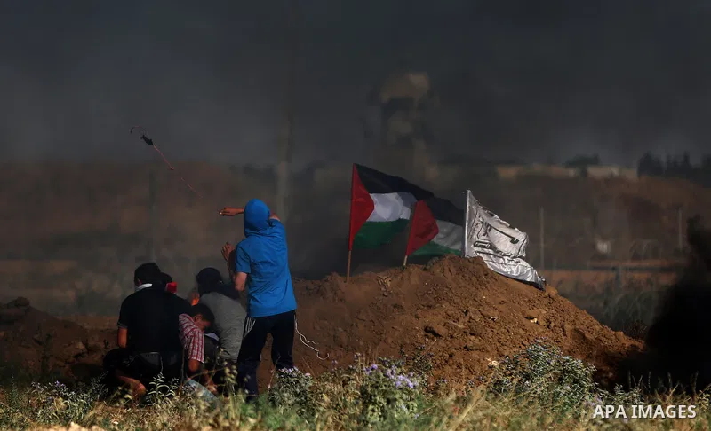 Palestinian protesters take cover during clashes with Israeli security forces following a demonstration against the blockade on the Gaza Strip, near the border fence east of Jabalia refugee camp on June 7, 2017. Photo by...