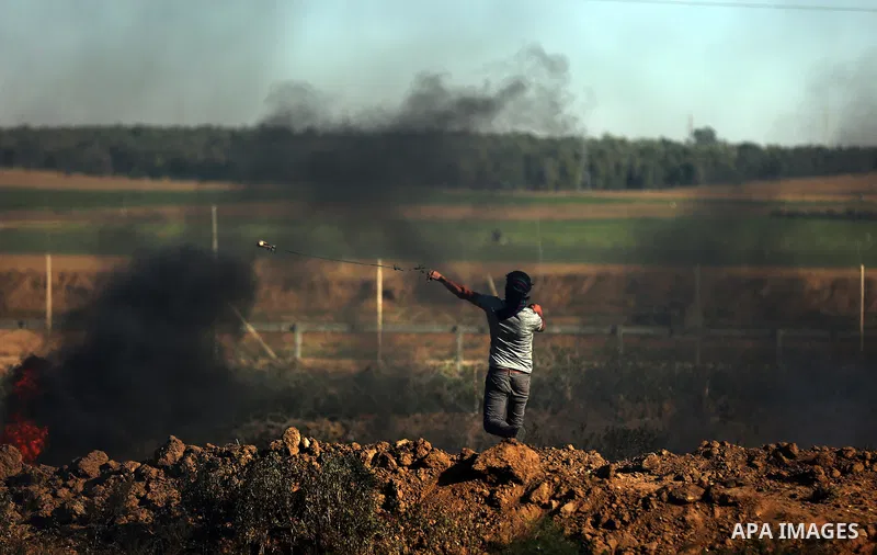A Palestinian protester uses a slingshot to hurl stones towards Israeli security forces during clashes following a demonstration against the blockade on the Gaza Strip, near the border fence east of Jabalia refugee camp...