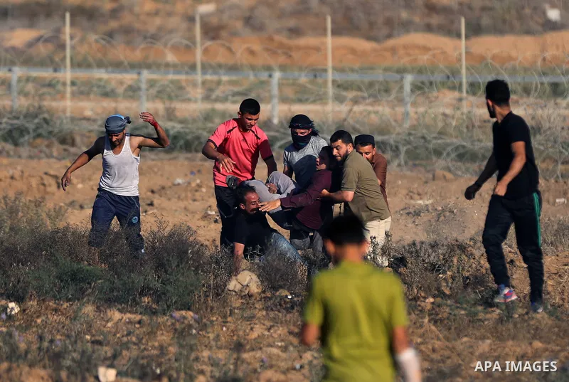 Palestinian protesters carry a wounded man during clashes with Israeli security forces following a demonstration against the blockade on the Gaza Strip, near the border fence east of Jabalia refugee camp on June 7, 2017....