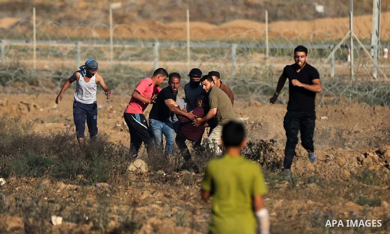 Palestinian protesters carry a wounded man during clashes with Israeli security forces following a demonstration against the blockade on the Gaza Strip, near the border fence east of Jabalia refugee camp on June 7, 2017....