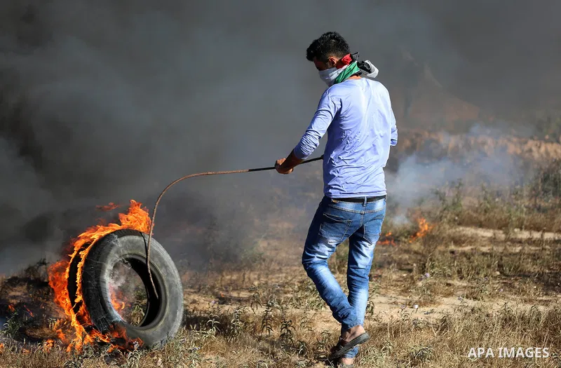A Palestinian protester takes cover during clashes with Israeli security forces following a demonstration against the blockade on the Gaza Strip, near the border fence east of Jabalia refugee camp on June 7, 2017. Photo...