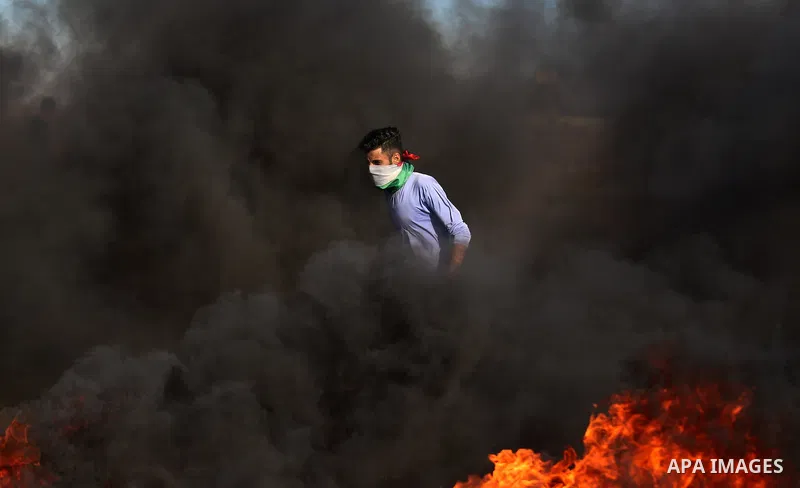 A Palestinian protester takes cover during clashes with Israeli security forces following a demonstration against the blockade on the Gaza Strip, near the border fence east of Jabalia refugee camp on June 7, 2017. Photo...
