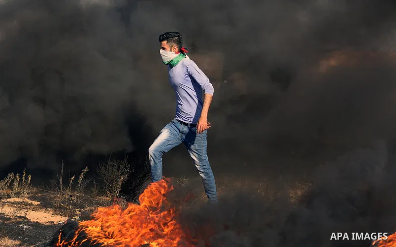 A Palestinian protester takes cover during clashes with Israeli security forces following a demonstration against the blockade on the Gaza Strip, near the border fence east of Jabalia refugee camp on June 7, 2017. Photo...