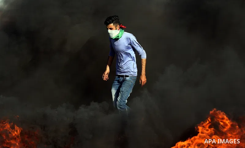 A Palestinian protester takes cover during clashes with Israeli security forces following a demonstration against the blockade on the Gaza Strip, near the border fence east of Jabalia refugee camp on June 7, 2017. Photo...