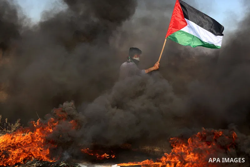 A Palestinian protester waves the national during clashes with Israeli security forces following a protest near the border fence east of Jabalia refugee camp, against the blockade on the Gaza Strip on June 7, 2017. Photo...
