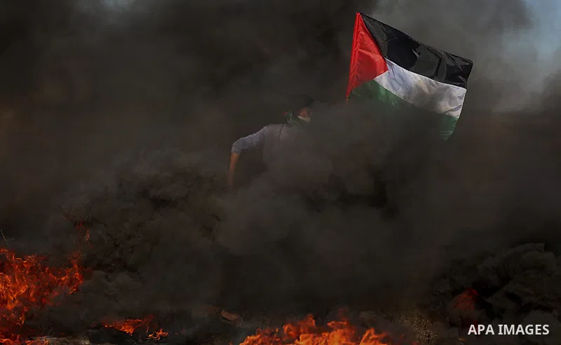 A Palestinian protester waves the national during clashes with Israeli security forces following a protest near the border fence east of Jabalia refugee camp, against the blockade on the Gaza Strip on June 7, 2017. Photo...