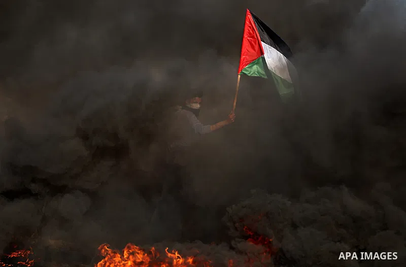 A Palestinian protester waves the national during clashes with Israeli security forces following a protest near the border fence east of Jabalia refugee camp, against the blockade on the Gaza Strip on June 7, 2017. Photo...