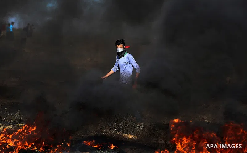 A Palestinian protester takes cover during clashes with Israeli security forces following a demonstration against the blockade on the Gaza Strip, near the border fence east of Jabalia refugee camp on June 7, 2017. Photo...