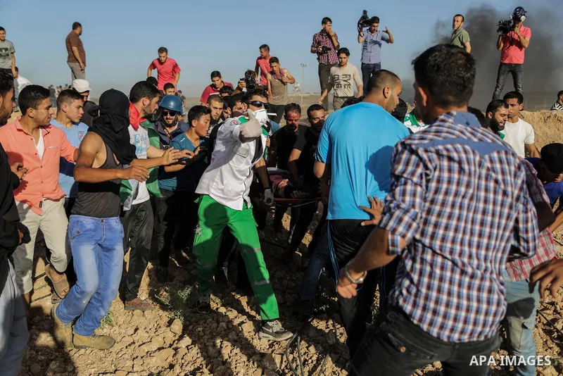 Palestinian protesters carry a wounded man during clashes with Israeli security forces following a demonstration against the blockade on the Gaza Strip, near the border fence east of Jabalia refugee camp on June 7, 2017....