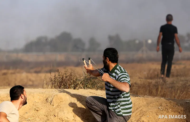A Palestinian protester uses a slingshot to hurl stones towards Israeli security forces during clashes following a demonstration against the blockade on the Gaza Strip, near the border fence east of Jabalia refugee camp...