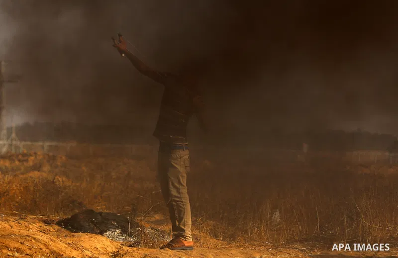Palestinian protesters take cover during clashes with Israeli security forces following a demonstration against the blockade on the Gaza Strip, near the border fence east of Jabalia refugee camp on June 9, 2017. Photo by...