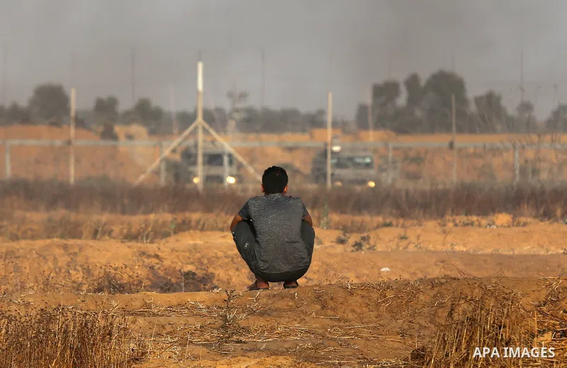 Palestinian protesters take cover during clashes with Israeli security forces following a demonstration against the blockade on the Gaza Strip, near the border fence east of Jabalia refugee camp on June 9, 2017. Photo by...