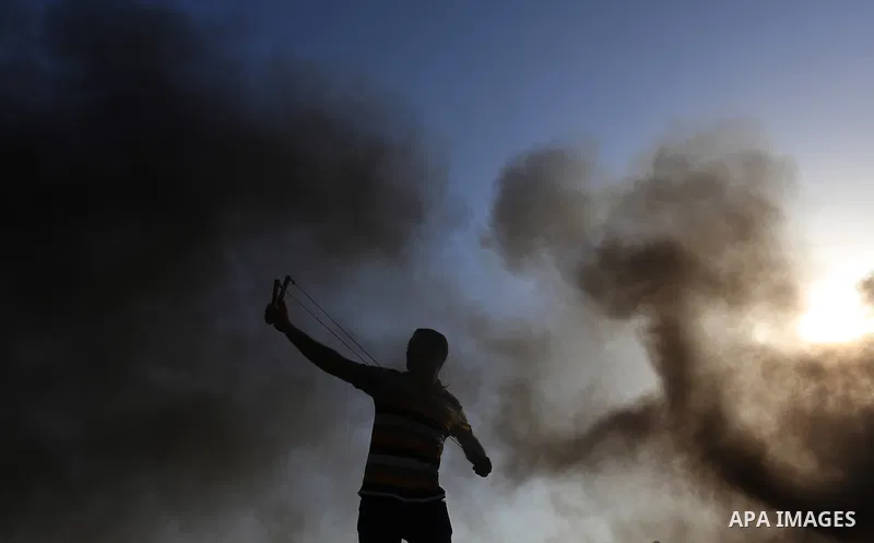 A Palestinian protester uses a slingshot to hurl stones towards Israeli security forces during clashes following a demonstration against the blockade on the Gaza Strip, near the border fence east of Jabalia refugee camp...