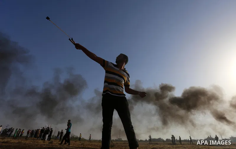 A Palestinian protester uses a slingshot to hurl stones towards Israeli security forces during clashes following a demonstration against the blockade on the Gaza Strip, near the border fence east of Jabalia refugee camp...