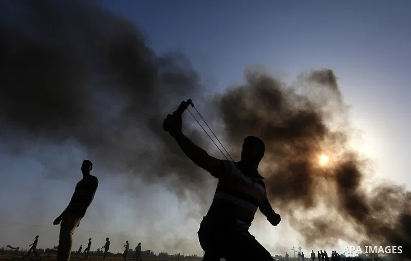 A Palestinian protester uses a slingshot to hurl stones towards Israeli security forces during clashes following a demonstration against the blockade on the Gaza Strip, near the border fence east of Jabalia refugee camp...
