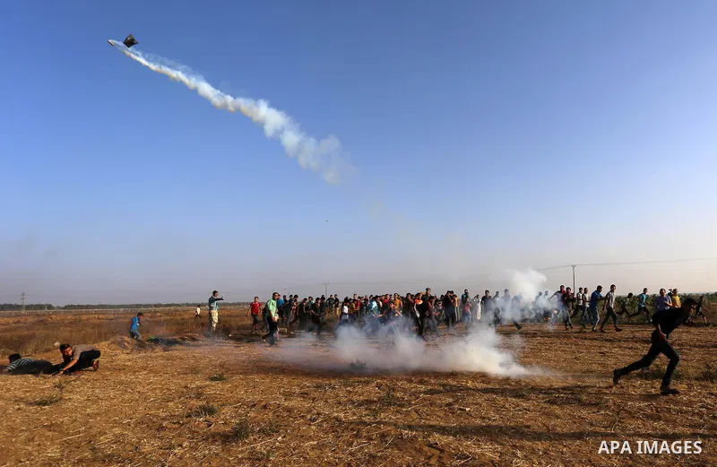 A Palestinian protester throws a tear gas canister towards Israeli security forces during clashes following a demonstration against the blockade on the Gaza Strip, near the border fence east of Jabalia refugee camp on Ju...