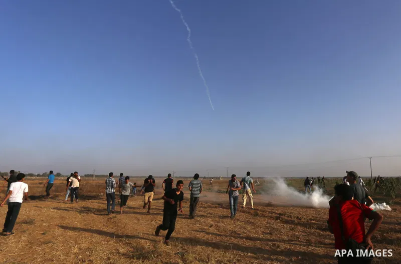 Palestinian protesters take cover during clashes with Israeli security forces following a demonstration against the blockade on the Gaza Strip, near the border fence east of Jabalia refugee camp on June 9, 2017. Photo by...