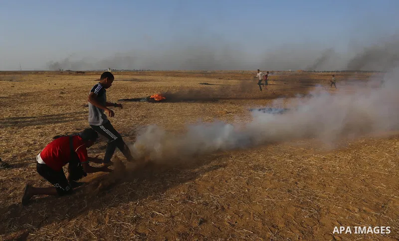 A Palestinian protester throws a tear gas canister towards Israeli security forces during clashes following a demonstration against the blockade on the Gaza Strip, near the border fence east of Jabalia refugee camp on Ju...