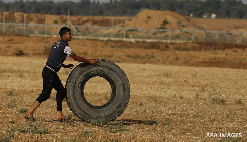 A Palestinian protester burns tires during clashes with Israeli security forces following a demonstration against the blockade on the Gaza Strip, near the border fence east of Jabalia refugee camp on June 9, 2017. Photo...