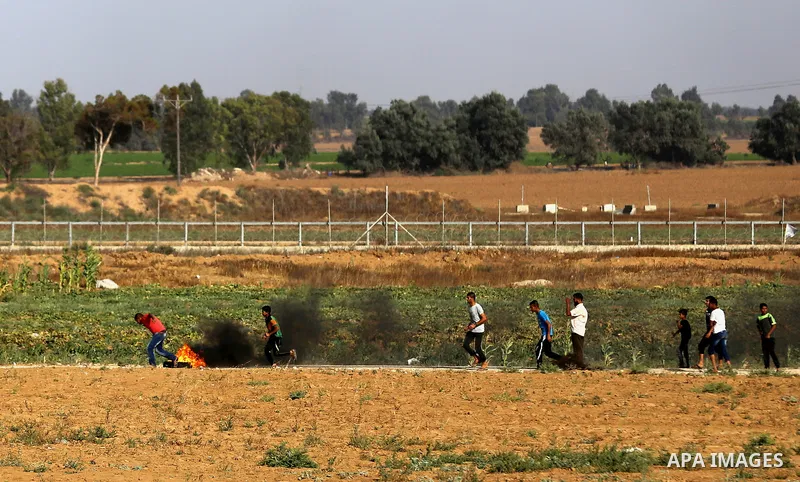 Palestinian protesters take cover during clashes with Israeli security forces following a demonstration against the blockade on the Gaza Strip, near the border fence east of Jabalia refugee camp on June 9, 2017. Photo by...