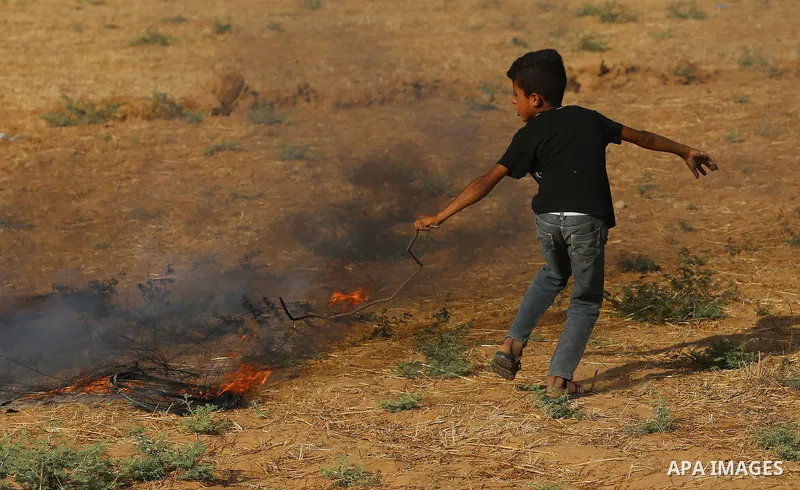 Palestinian protesters take cover during clashes with Israeli security forces following a demonstration against the blockade on the Gaza Strip, near the border fence east of Jabalia refugee camp on June 9, 2017. Photo by...