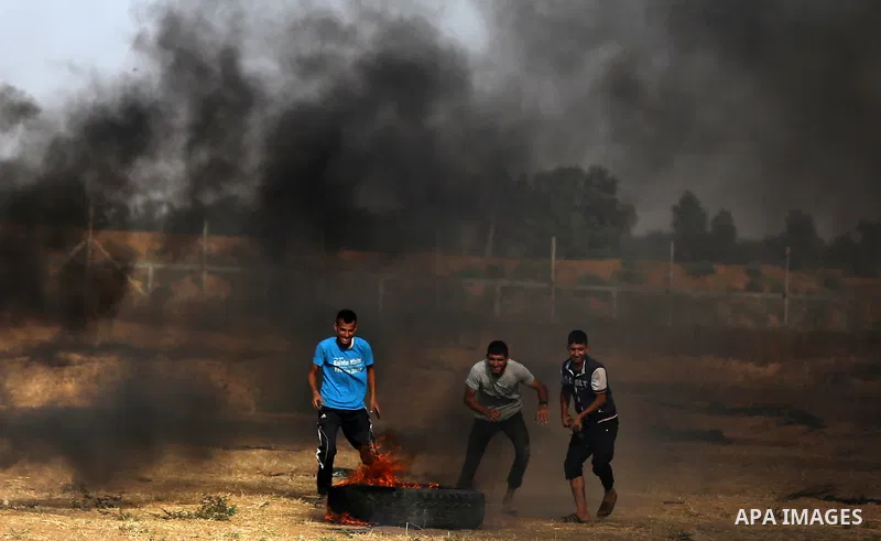 Palestinian protesters take cover during clashes with Israeli security forces following a demonstration against the blockade on the Gaza Strip, near the border fence east of Jabalia refugee camp on June 9, 2017. Photo by...