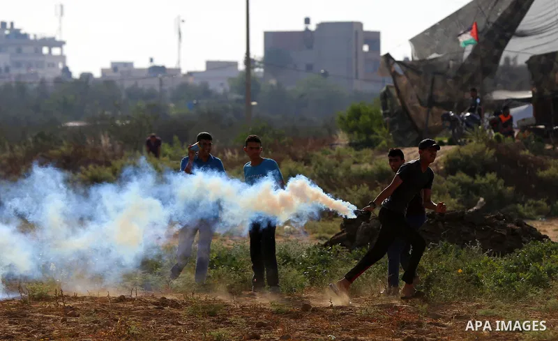 A Palestinian protester throws a tear gas canister towards Israeli security forces during clashes following a demonstration against the blockade on the Gaza Strip, near the border fence east of Jabalia refugee camp on Ju...