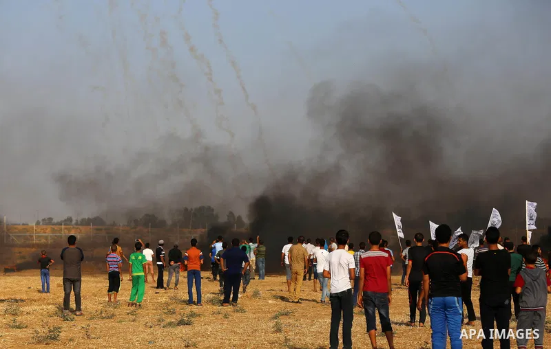 Palestinian protesters take cover during clashes with Israeli security forces following a demonstration against the blockade on the Gaza Strip, near the border fence east of Jabalia refugee camp on June 9, 2017. Photo by...